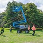 Group of people maypole dancing around a cherry picker