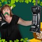 1 women with a fake green moustache holding an inflatable phones with the background image of st patricks da