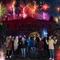 group of people in front of building with fireworks around them 