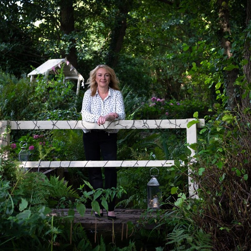 Woman standing on small bridge in woodland