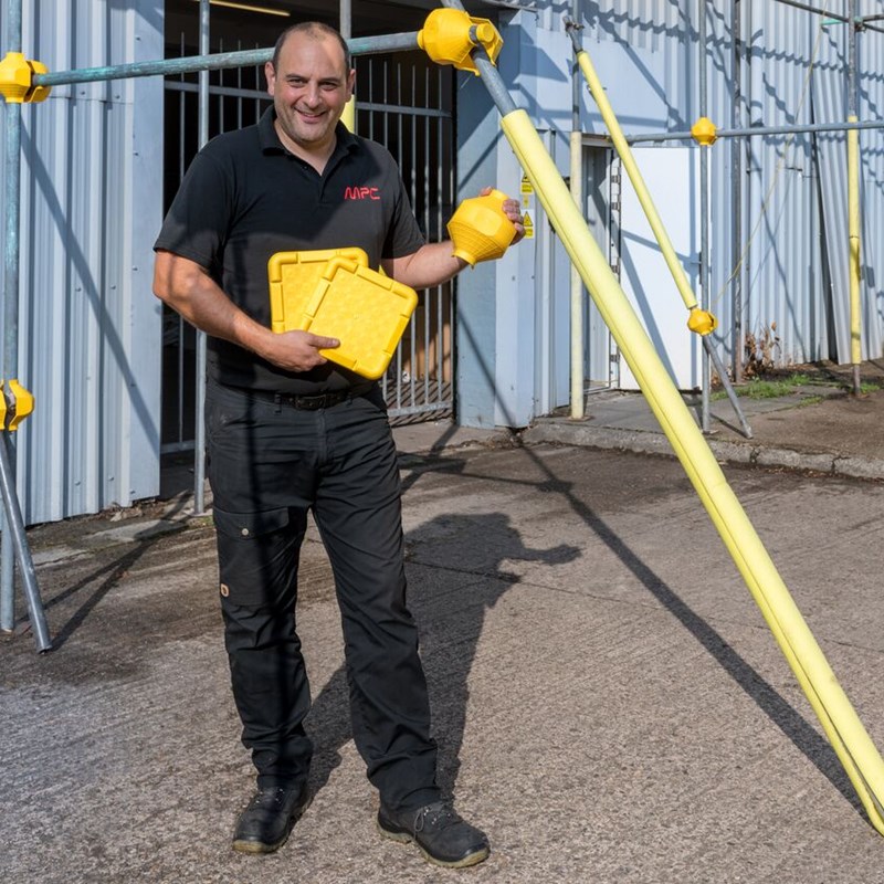 Man infront of scaffolding holding scaffold components