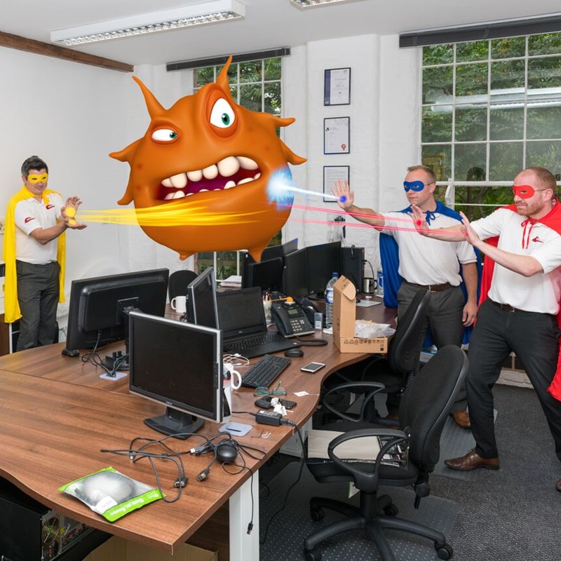 3 men dressed as superheros in office blasting light at an orange monster floating above a desk.