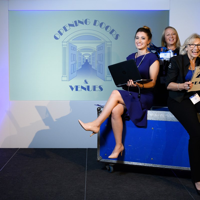 3 women posing on a stage sat on a cabinet