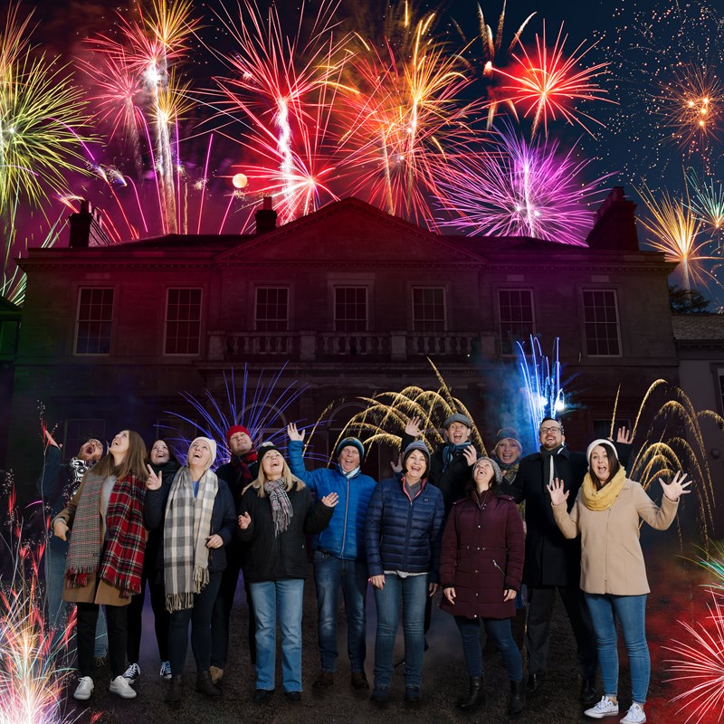 group of people in front of building with fireworks around them