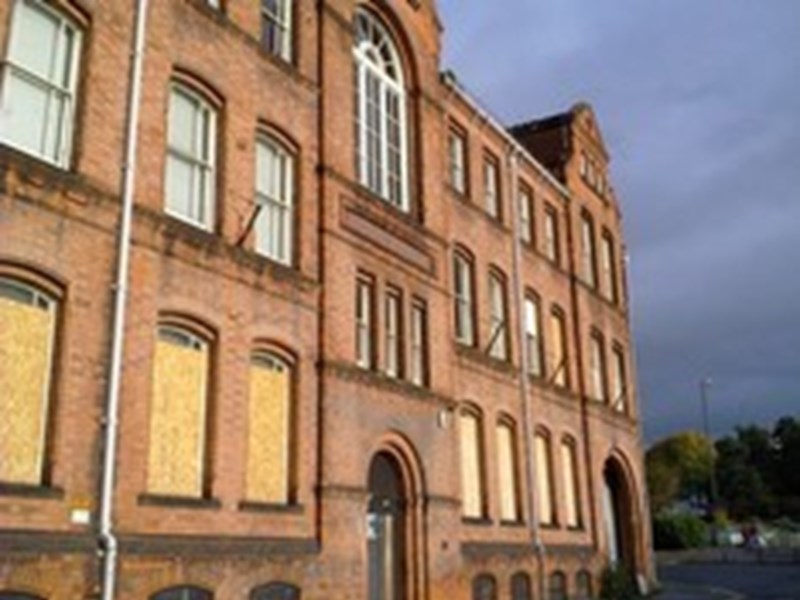 Image shows large listed red brick building