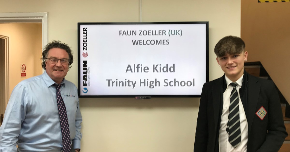 Image shows Alfie Kidd and Simon Hyde standing either side of a TV screen which shows a welcome message for Alfie